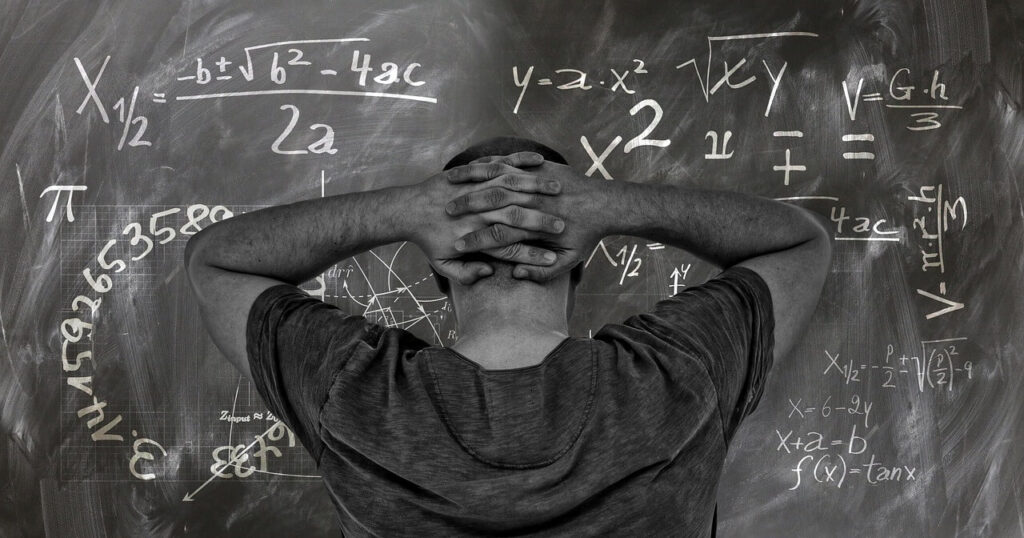 man in front of chalkboard staring at math problem